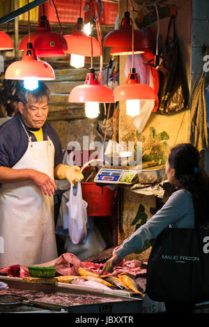Portrait vertical d'un client d'acheter du poisson à l'étal des poissonniers dans le marché traditionnel à Hong Kong, Chine. Banque D'Images