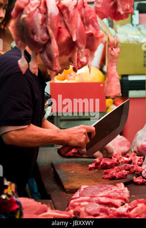 Portrait vertical d'une boucherie hacher des morceaux de viande sur un marché humide à Hong Kong, Chine. Banque D'Images