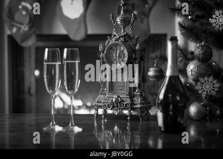 Image en noir et blanc de deux verres de champagne à table à côté de Old clock show à 12 heures. Noël fond monochrome Banque D'Images