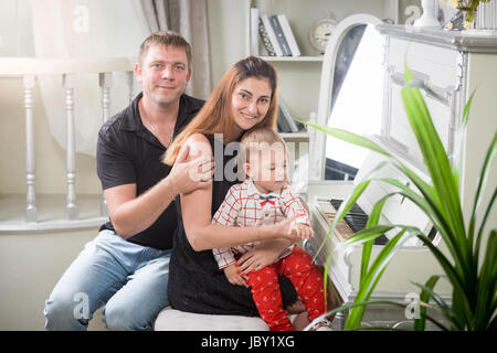 Portrait de belle jeune famille avec bébé garçon jouant au piano Banque D'Images