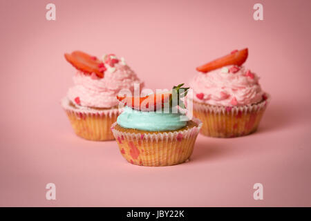 Libre studio shot of three cupcakes avec fraise sur fond rose Banque D'Images