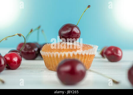 Muffin maison décorée avec cerise sur fond bleu Banque D'Images