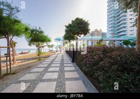 Une vue d'été de la plage dans la région de Limassol à Chypre dans Neapoli, près de l'Olympic Residence. Une vue sur la mer, le chemin piétonnier, de la plage de sable et de deux tours jumelles. Banque D'Images