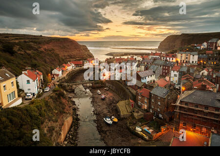 L'aube alors que le soleil commence à se lever sur le magnifique village de pêcheurs de Staithes, niché dans les falaises de la côte du Yorkshire du Nord. Banque D'Images