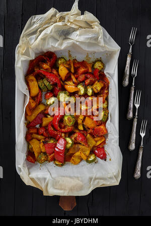 Plat de cuisson avec un mélange de légumes grillés : courgettes, poivrons rouges et jaunes, tomates cerises mélangée avec le curry. Vue supérieure de la photo. Banque D'Images