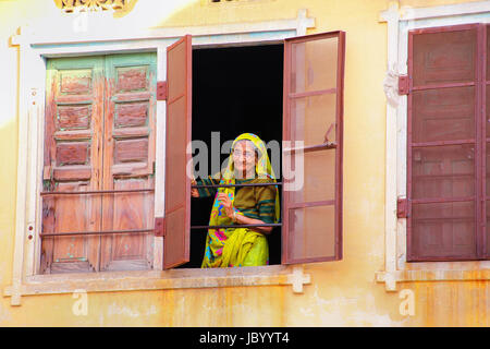 Femme regardant par la fenêtre à Jaipur, Rajasthan, Inde. Jaipur est la capitale et la plus grande ville du Rajasthan. Banque D'Images