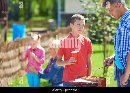 Portrait de jeune homme la friture des saucisses et de parler à son fils à la campagne le week-end. Banque D'Images