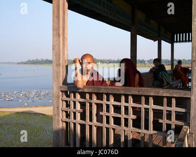 Un moine posé sur u-bein bridge près de Mandalay Myanmar Banque D'Images