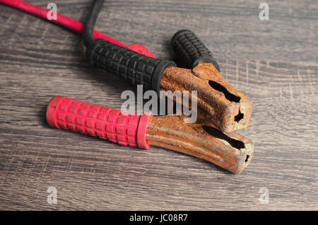 Câbles de raccordement pour recharger la batterie de voiture. Rouge et noir, le câble positif et négatif sur un fond de bois. Banque D'Images
