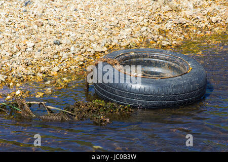 Un pneu et jante désaffectée d'un petit cours d'eau polluantes sur le Solent Way Beach sur l'eau près de Southampton dans le Hampshire Titchfield Banque D'Images