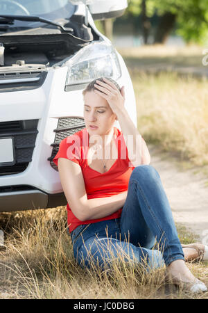 Contrarié woman and leaning on casse voiture Banque D'Images