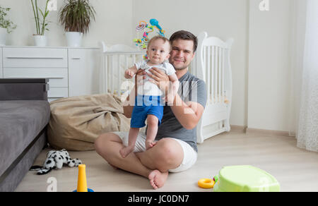 Heureux jeune père jouer avec son bébé de 9 mois garçon sur marbre au salon Banque D'Images