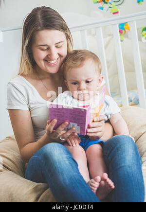 Portrait de bébé adorable garçon assis sur les genoux des mères et reading book Banque D'Images