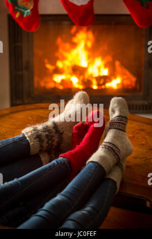 Chaussettes tricotées en famille assis dans le chalet par cheminée à bois Banque D'Images