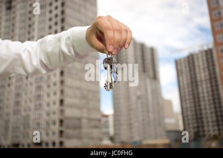 Young businessman holding keys de nouveau au site de construction immobilier Banque D'Images