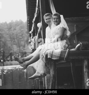 Photo en noir et blanc de newlyweds sitting on pier et de rire Banque D'Images
