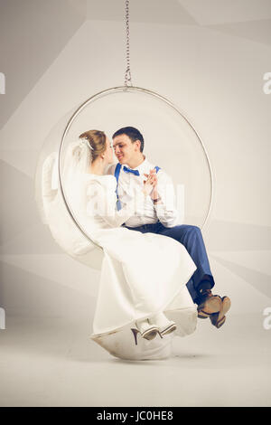 Photo aux couleurs de l'heureux couple assis sur chaise en plastique au studio Banque D'Images