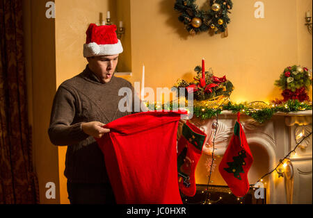 Portrait de jeune homme dans Red Hat à l'intérieur de Santa sac avec étonnement Banque D'Images