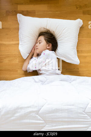 Portrait de petite fille dormir sur un plancher en bois sur un oreiller blanc Banque D'Images