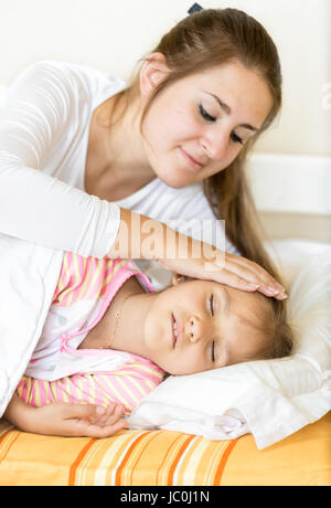 Portrait de mère tenant la main sur sa fille dormir avec soin