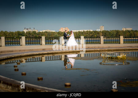 Belle mariée et le marié tenant la main et danser à riverbank Banque D'Images