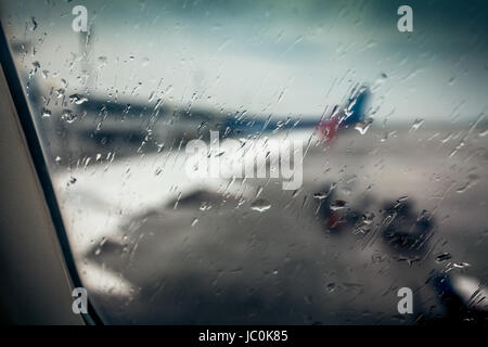 Vue de flou artistique sur l'aile d'avion par la fenêtre passager avec gouttes de pluie Banque D'Images