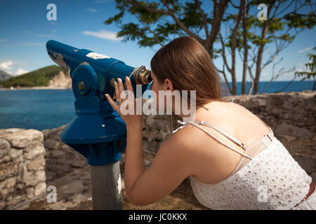 Jeune femme à la recherche sur le paysage à travers un télescope à monnayeur touristique Banque D'Images