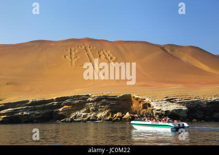 Groupe touristique dans un bateau près de candélabres des Andes dans la région de Pisco Bay, au Pérou. Candélabres est bien connu sur le géoglyphe préhistorique face nord de Banque D'Images