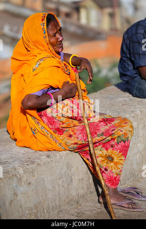 Femme en sari coloré assis sur un mur de pierre, Jaipur, Inde. Jaipur est la capitale et la plus grande ville de l'état indien du Rajasthan. Banque D'Images