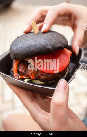 Photo gros plan de woman holding burger de boeuf avec sol en marbre noir Banque D'Images