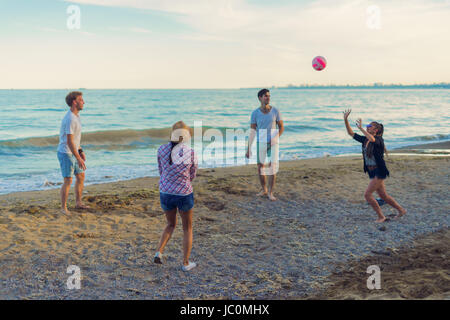 Les amis jouer au volley sur une plage sauvage pendant le coucher du soleil Banque D'Images