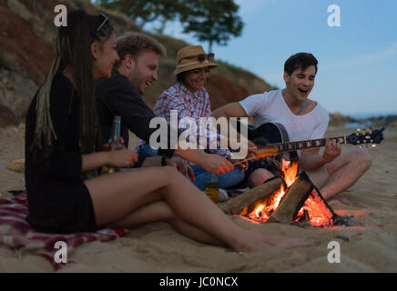 Amis assis sur la plage. l'homme est de jouer de la guitare. Banque D'Images