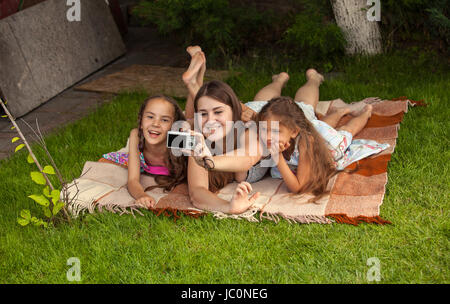 Smiling mother et deux filles faisant des photos d'eux-mêmes à park Banque D'Images