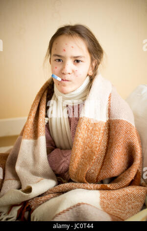 Portrait de jeune fille malade de la varicelle avec mesure de la température avec le thermomètre de la bouche Banque D'Images