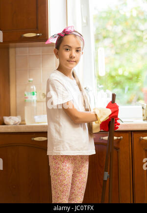 Portrait of smiling girl posing on cuisine sale avec un balai et une pelle Banque D'Images