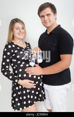 Portrait of happy smiling pregnant couple posing avec de petites bottes bébé Banque D'Images