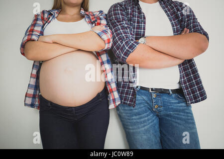 Tonique photo gros plan de la femme enceinte et son mari s'appuyant sur mur blanc Banque D'Images