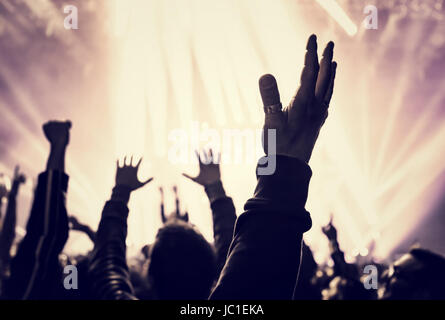 Grunge style photo de silhouette de personnes les mains levées jusqu'au concert, écouter de la musique, dance club, vie nocturne active concept Banque D'Images