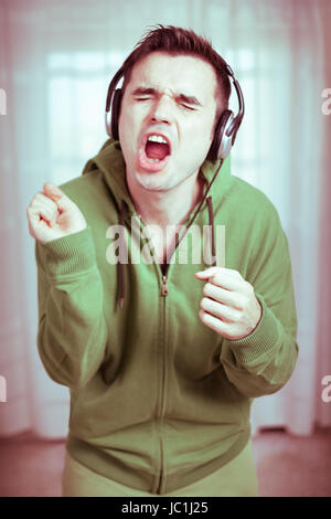 Crazy casual young man with headphones le chant. Banque D'Images