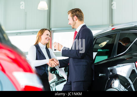 Vendeur ou vendeur de voiture et client en concession, ils se serrer la main, les mains sur les clés de voiture et le joint de l'achat de la nouvelle voiture ou auto Banque D'Images