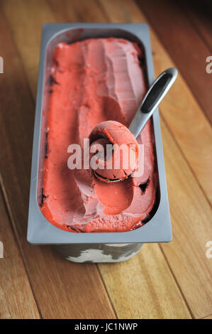 Fraise Bio faits maison cuillère à crème glacée de fruits, creusées dans un contenant de Banque D'Images