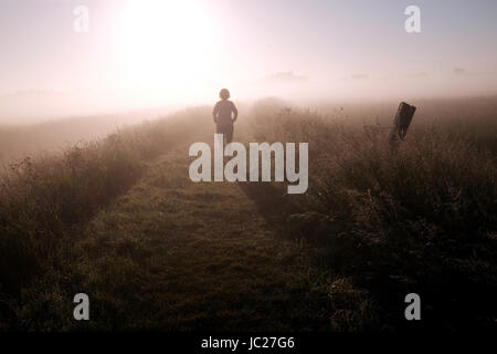 Suffolk Aldeburgh, UK. 14 Juin, 2017. Un marcheur est enveloppé dans un beau brouillard tôt le matin qu'elle est brûlée par le soleil au cours de l'estuaire de la rivière Alde à Aldeburgh sur la côte du Suffolk . Beau temps chaud devrait se répandre à travers la Grande-Bretagne à nouveau dans les prochains jours avec des températures atteignant jusqu'à 28 degrés dans certaines régions Crédit : Simon Dack/Alamy Live News Banque D'Images