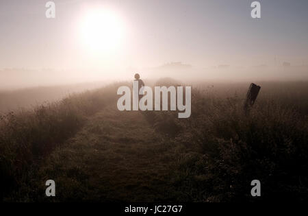 Suffolk Aldeburgh, UK. 14 Juin, 2017. Un marcheur est enveloppé dans un beau brouillard tôt le matin qu'elle est brûlée par le soleil au cours de l'estuaire de la rivière Alde à Aldeburgh sur la côte du Suffolk . Beau temps chaud devrait se répandre à travers la Grande-Bretagne à nouveau dans les prochains jours avec des températures atteignant jusqu'à 28 degrés dans certaines régions Crédit : Simon Dack/Alamy Live News Banque D'Images