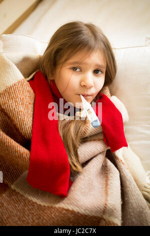 Portrait de petite fille au lit et la tenue en bouche thermomètre Banque D'Images