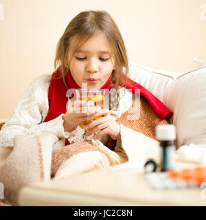 Portrait de petite fille malade au lit et en soufflant sur le thé chaud Banque D'Images