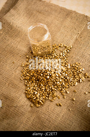 Pile de balayé des pépites d'or et d'un bocal en verre sur de la toile de jute Banque D'Images