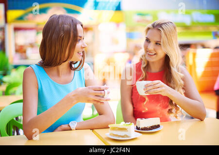 Portrait de deux jeunes filles ayant les gâteaux avec le café cafe Banque D'Images