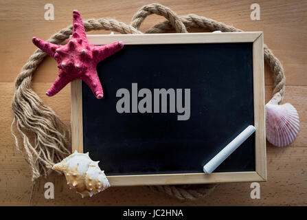 Closeup shot of small blackboard décorées avec des coquillages et des étoiles de mer rouge Banque D'Images