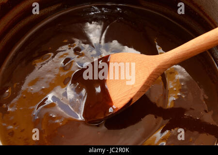 Le chocolat noir fondu dans une casserole, d'être remué avec une cuillère en bois Banque D'Images