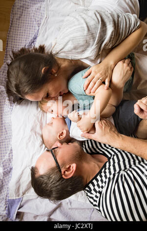 Les jeunes parents avec des petits enfants au lit. Banque D'Images